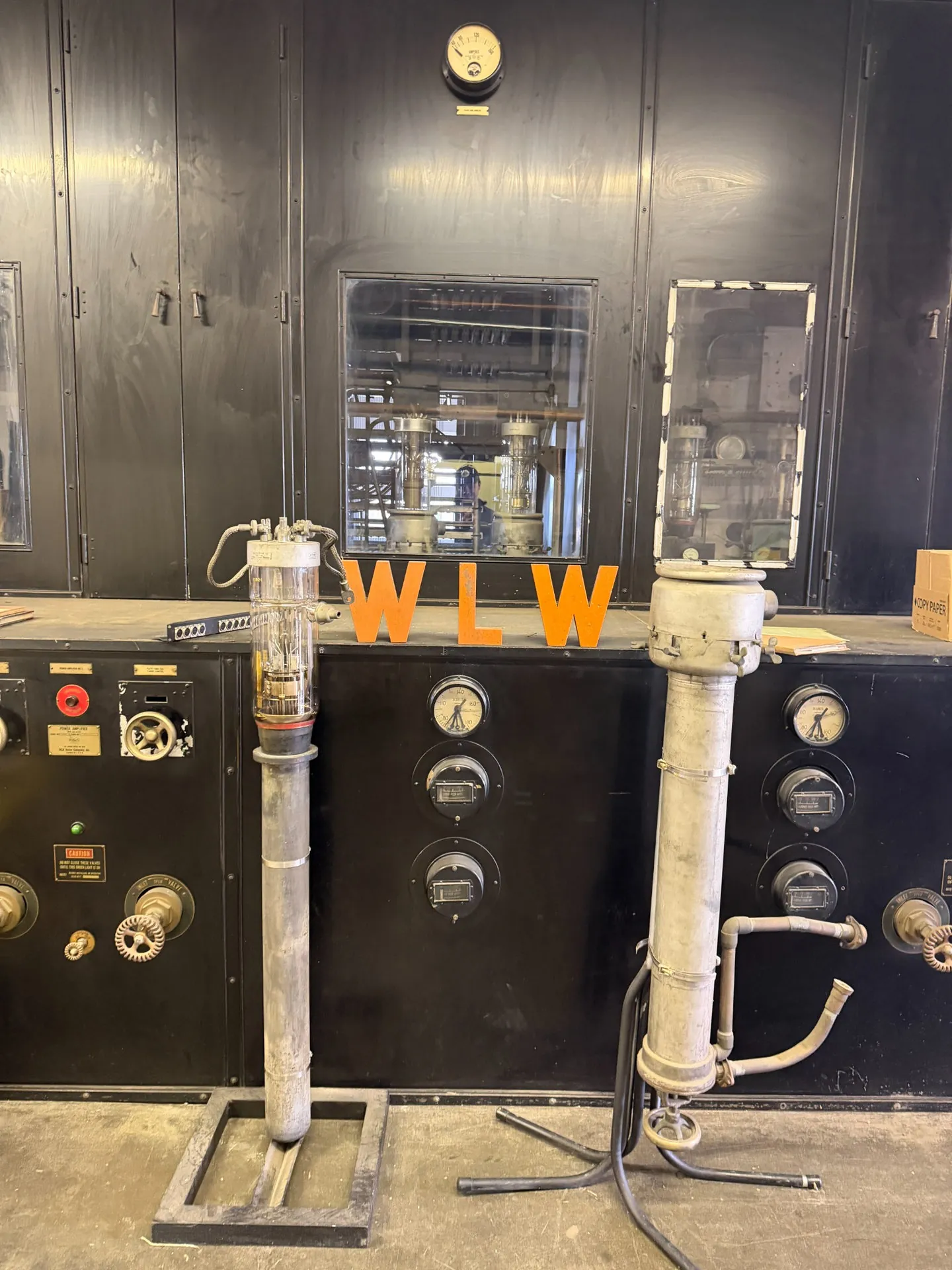 Close-up of WLW letters, glass electrical equipment and gauges in front of black vintage transmitter cabinets