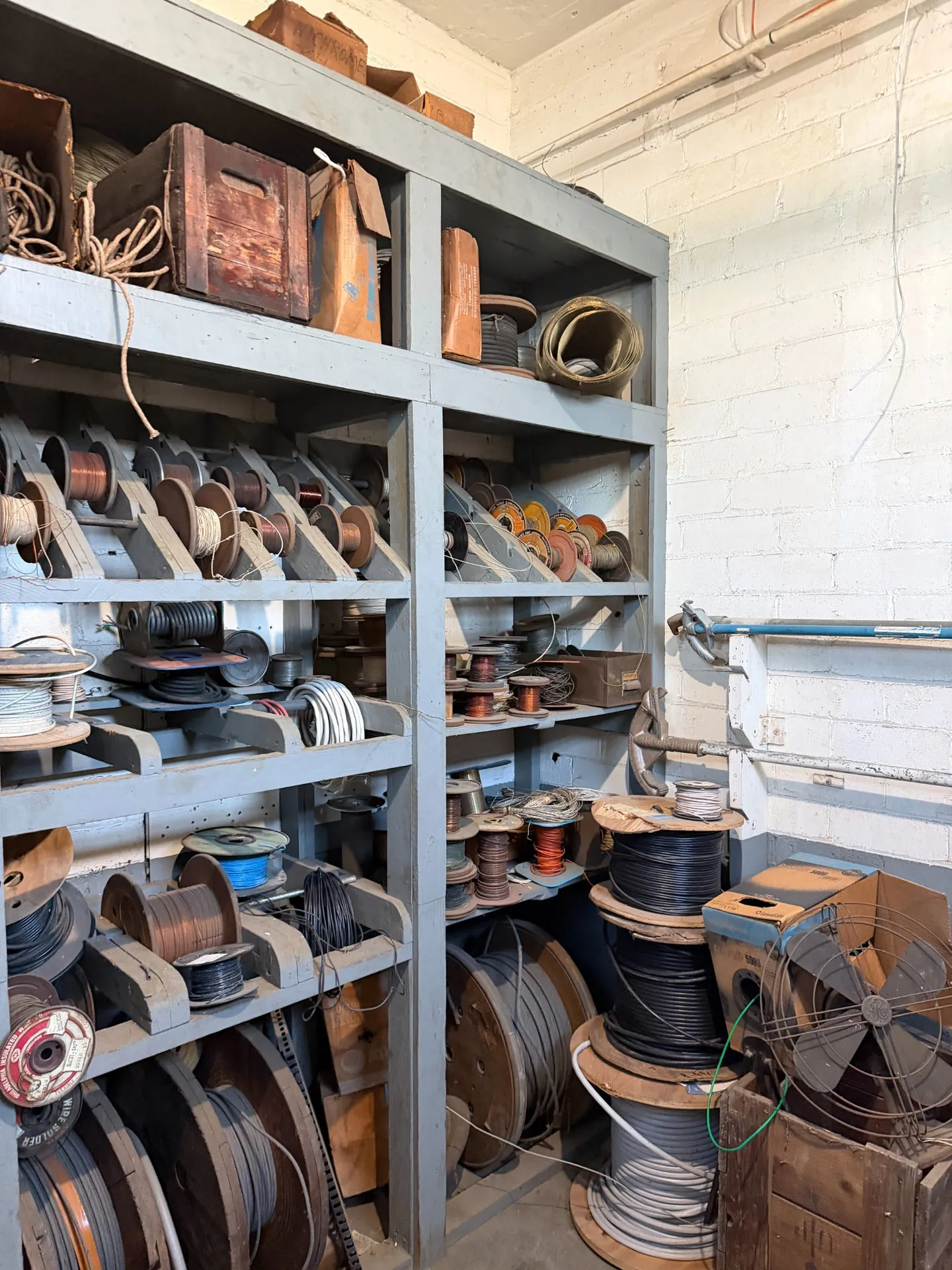 Shelves of spooled electrical wire and aged materials in an old transmitter building storage room